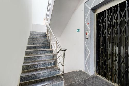 a staircase in a building with a black door at Super Hotel O Chandanagar Formerly Nakshatra in Lingampalli