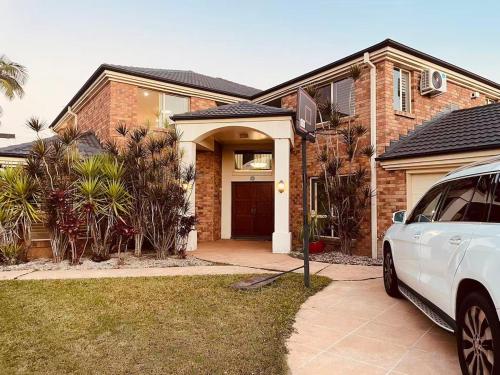 a white car parked in front of a brick house at Spacious Family Retreat with Pool in Carindale in Brisbane
