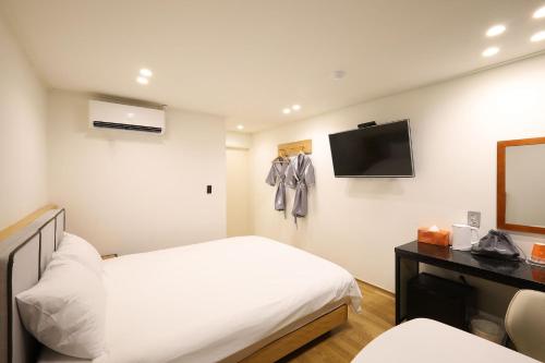a hotel room with two beds and a television at JB Plus Hotel in Busan