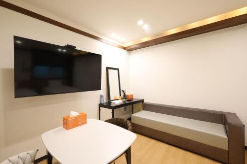 a room with a bed and a table and a mirror at JB Plus Hotel in Busan