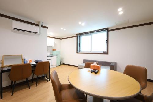 a room with a table and chairs and a kitchen at JB Plus Hotel in Busan