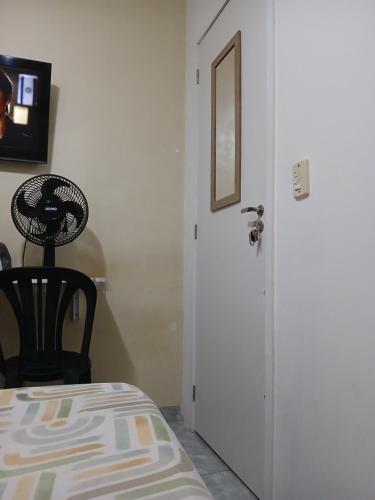 a room with a white door and a black chair at Quarto Privado Cama Casal e Individuais Apto in Rio de Janeiro