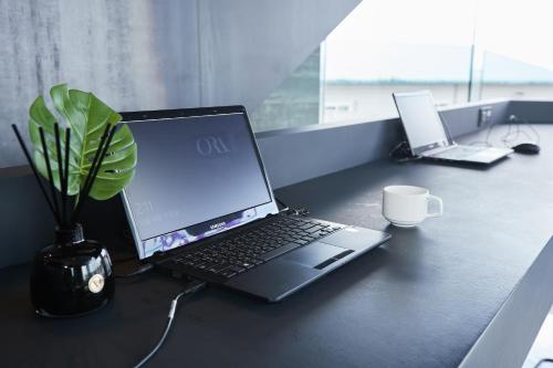a laptop computer sitting on a desk with a potted plant at Hotel ORA Incheon in Incheon