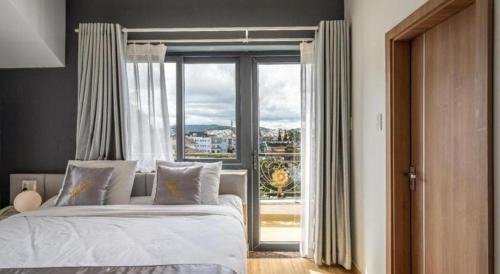 a bedroom with a bed and a large window at Gold View Boutique Hotel Đà Lạt in Da Lat