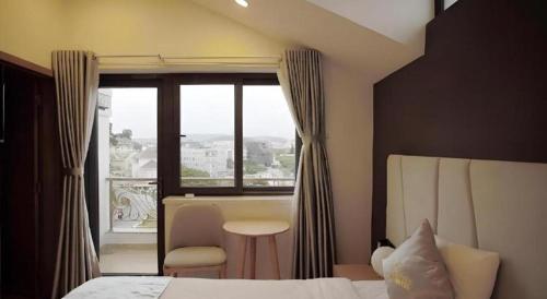 a bedroom with a bed and a window with a chair at Gold View Boutique Hotel Đà Lạt in Da Lat