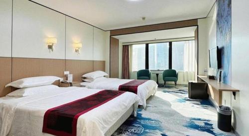 a hotel room with two beds and a television at Dalian Bohai Pearl Hotel in Dalian