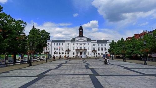a large white building with a clock tower on top at Apartament Okrzei in Płock
