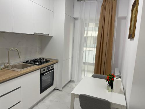 a kitchen with a sink and a stove and a table at Modern Studio With Balcony - Unirea Towers Iasi in Iaşi
