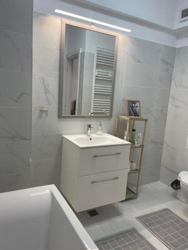 a white bathroom with a sink and a mirror at Modern Studio With Balcony - Unirea Towers Iasi in Iaşi