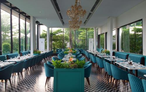 a long dining room with tables and chairs and a chandelier at TreeHouse Velis Sonipat in Sonīpat