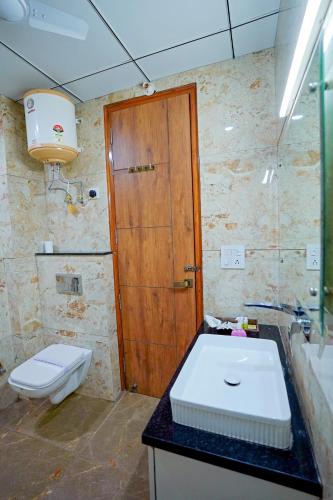 a bathroom with a toilet and a sink and a wooden door at Hotel Maharaja Palace Boutique Hotels Near Medanta Medicity Gurgaon in Gurgaon