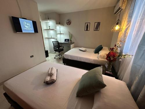 Una habitación de hotel con dos camas y un televisor. en CABO HoSTEL, en Ríohacha