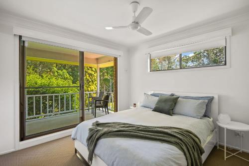 a bedroom with a bed and a balcony at Ocean & Golf in Mollymook