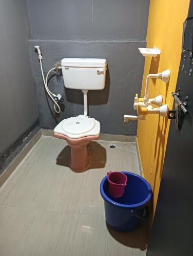 a bathroom with a toilet and a bucket at Lakshika beach resort in Gokarna