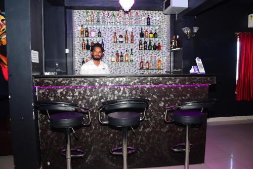 a man standing behind a bar with purple stools at TNV Residency in Pūrnānkuppam