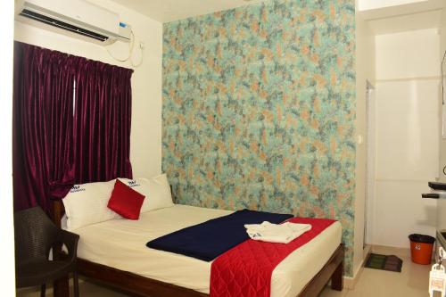 a small bedroom with a bed with a red blanket at TNV Residency in Pūrnānkuppam