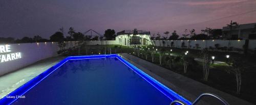 a swimming pool at night with a building in the background at NATURE GREEN faarm in Dahmi