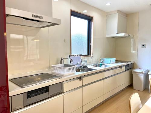 a kitchen with white cabinets and a sink and a window at Bliss上野 in Oita
