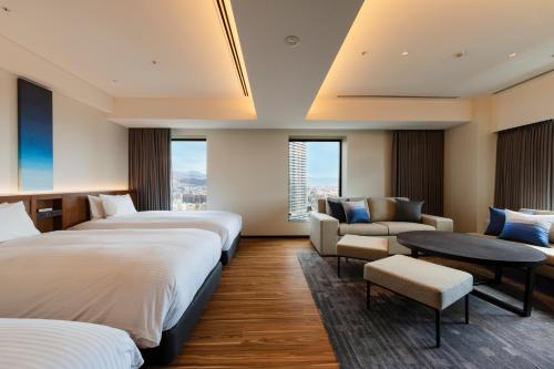 a hotel room with two beds and a couch at HOTEL GRANVIA HIROSHIMA SOUTH GATE in Hiroshima
