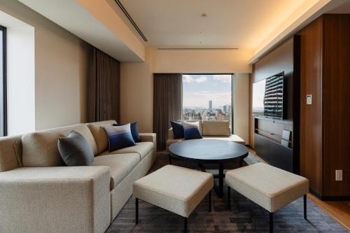 a living room with a couch and a table at HOTEL GRANVIA HIROSHIMA SOUTH GATE in Hiroshima