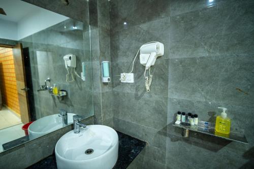a bathroom with a sink and a shower with a phone at Hotel The Royal Buddha in Bodh Gaya