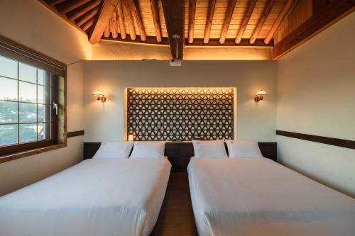 two beds in a room with a window at Luxury Hanok Garden Retreat in Incheon