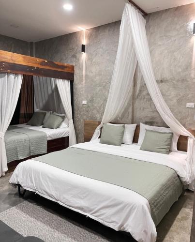 a bedroom with two beds with white curtains at บ้านพักบุหงา199 อ สรรพยา in Sanphaya