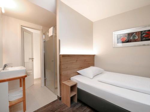 a small bedroom with a bed and a sink at B&B HOTEL Berlin-Mitte in Berlin