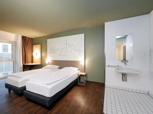 a hotel room with two beds and a sink at B&B HOTEL Berlin-Mitte in Berlin