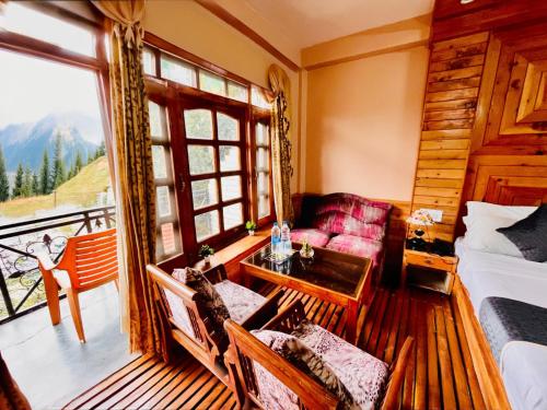 a room with a bed and a table and a window at Hotel Hollywood Manali - Scenic River & Mountain View With Premium Rooms Near Mall Road in Manāli
