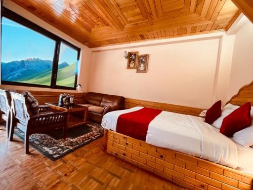 a bedroom with a bed and a couch and a window at Hotel Hollywood Manali - Scenic River & Mountain View With Premium Rooms Near Mall Road in Manāli