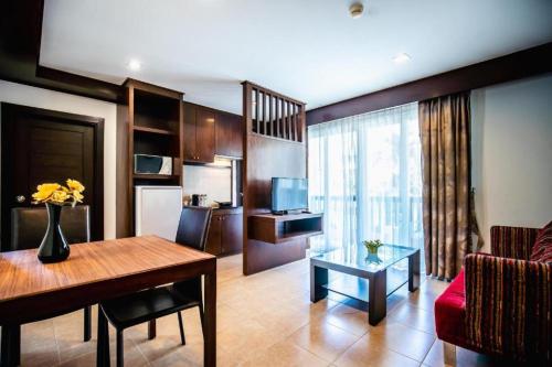 a living room with a table and a room with a couch at Ratana Hotel Chalong in Rawai Beach