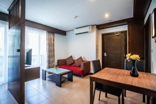 a living room with a red couch and a table at Ratana Hotel Chalong in Rawai Beach