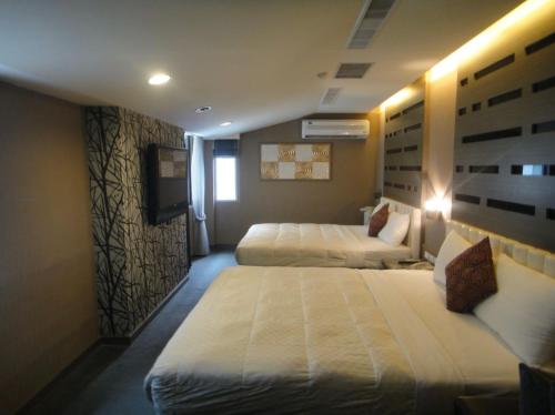 a hotel room with two beds and a television at Fu Kuang Hotel in Pingtung City