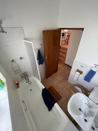 a bathroom with a tub and a sink and a toilet at Jocks Place (on the sea) in Bettyʼs Bay
