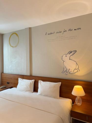 a bedroom with a bed with a picture of a rabbit on the wall at CHERN Bangkok in Bangkok