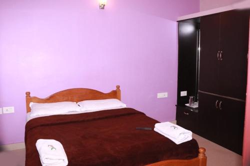 une chambre avec un lit et un mur violet dans l'établissement Greenyard cottage, à Ooty