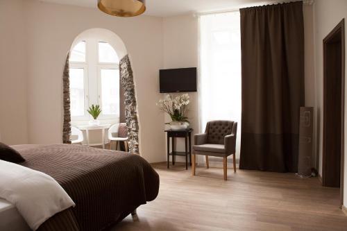 a bedroom with a bed and a chair and a table at Hotel Ravene in Cochem