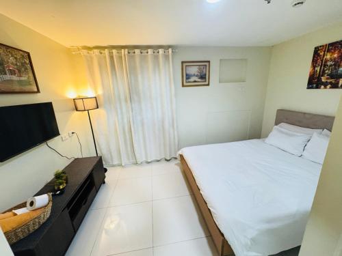 a small bedroom with a bed and a television at Brenthill Premium Condo Baguio City with Generator in Baguio