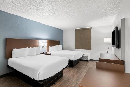 a hotel room with two beds and a flat screen tv at Suburban Studios Chester I-95 in Chester