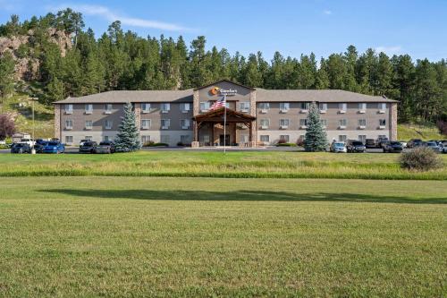 a large building with a large field in front of it at Comfort Inn & Suites in Custer