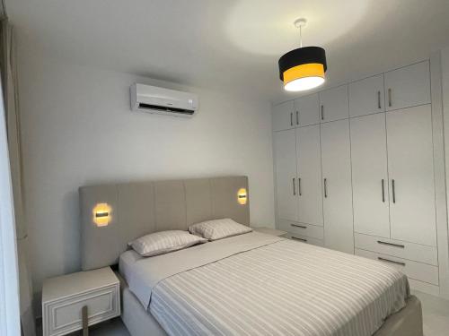 a white bedroom with a bed and a light at Penthouse Blueberry in Kérynia