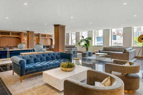 a living room with a blue couch and chairs at Cambria Hotel Detroit Downtown in Detroit