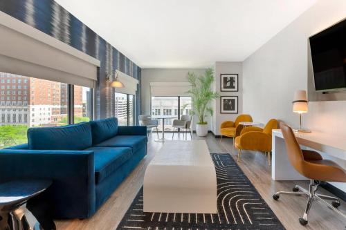 a living room with a blue couch and yellow chairs at Cambria Hotel Detroit Downtown in Detroit