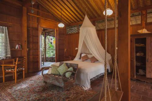 a bedroom with a bed with a canopy at Resort JUNGLEROOM Canggu in Canggu