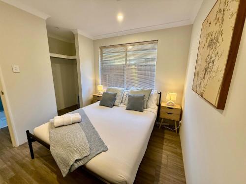 a bedroom with a large white bed and a window at 12 Beautiful Brabham Big Backyard 4br Parking in Perth