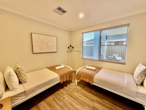 two beds in a room with a window at 12 Beautiful Brabham Big Backyard 4br Parking in Perth