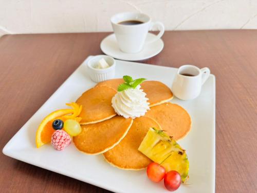 einen Teller Pfannkuchen mit Obst und eine Tasse Kaffee in der Unterkunft GLORY ISLAND OKINAWA Yabusachi Resort in Nanjō