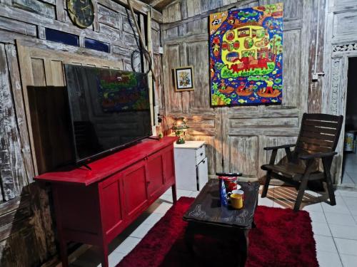 a living room with a red dresser and a painting on the wall at Eyang Residence Limasan Kebon Dalem in Potrojayan