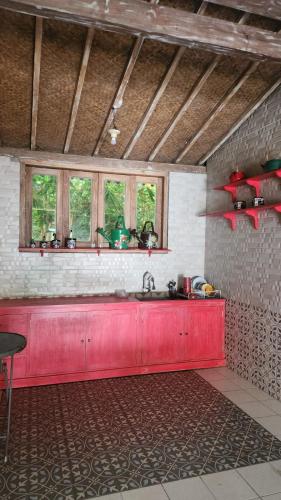 a kitchen with a red counter top and two windows at Eyang Residence Limasan Kebon Dalem in Potrojayan